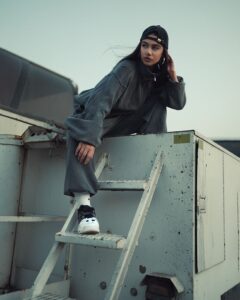 Editorial portrait of a person in muted streetwear on an industrial rooftop