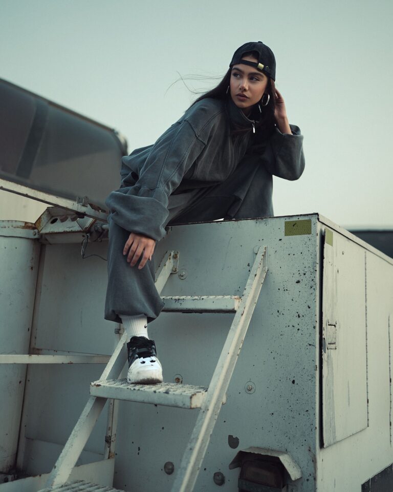 Editorial portrait of a person in muted streetwear on an industrial rooftop
